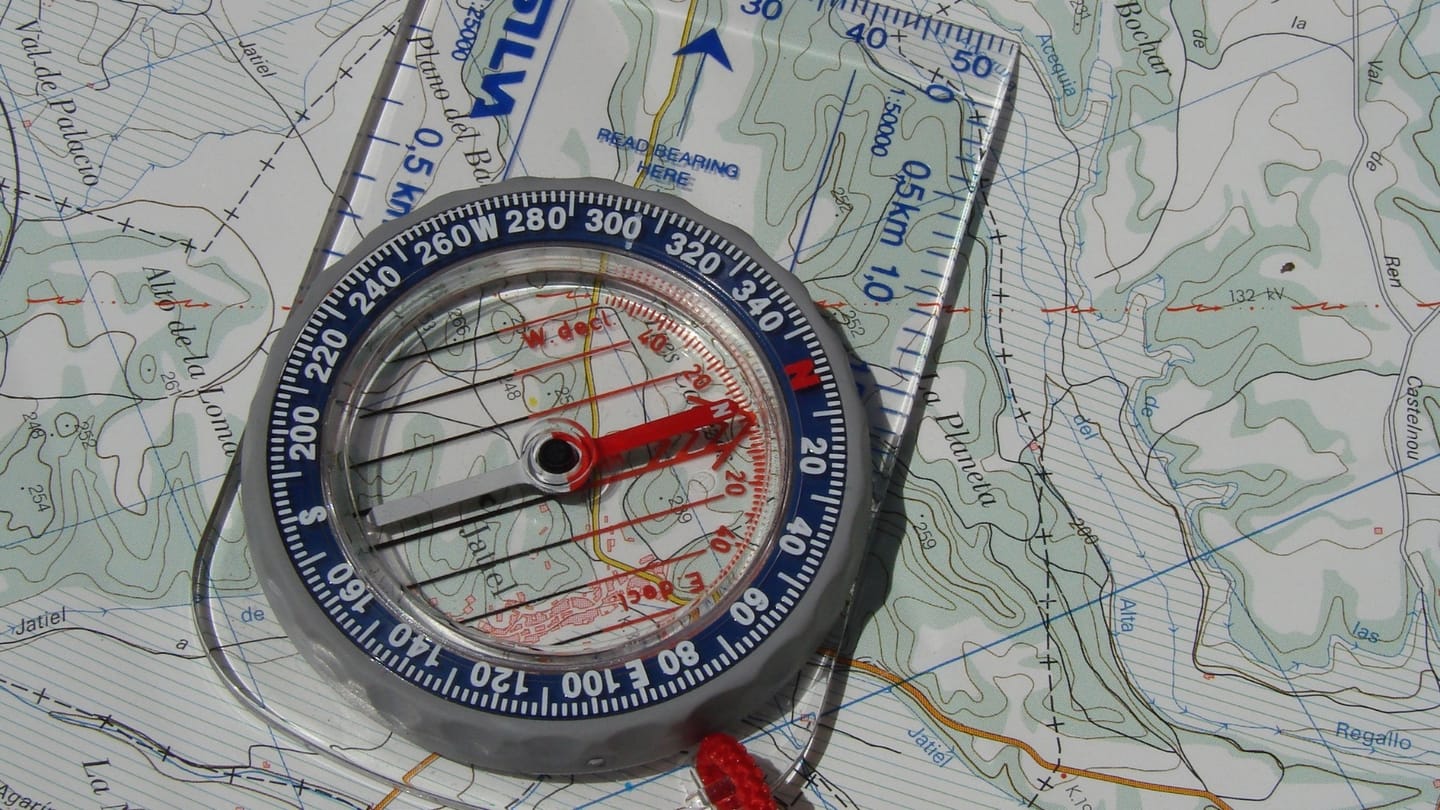 Brújula de placa apoyada sobre un mapa topográfico