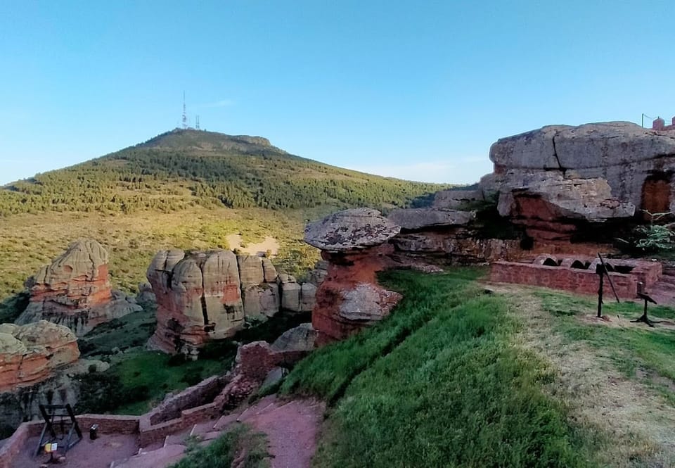 Peñas de arenisca roja erosionadas sobre una ladera de matorral, junto a Ojos Negros
