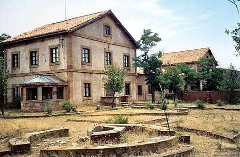 Edificio de la compañía minera, de dos plantas con galería acristalada, hoy abandonado entre la vegetación