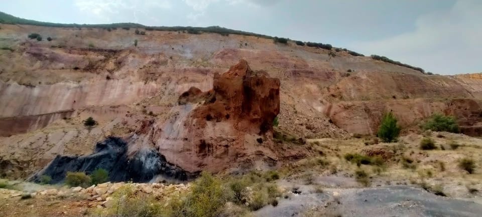Frente de la cantera a cielo abierto, con las vetas de mineral rojizo y ocre al descubierto
