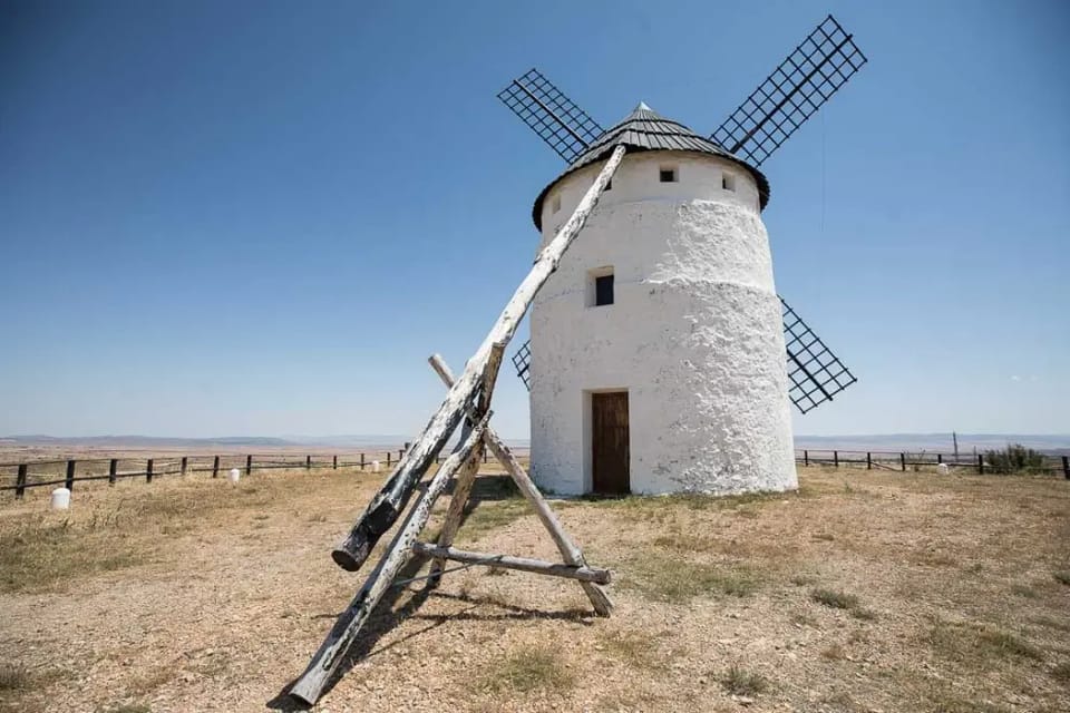 Molino de viento encalado con aspas de madera y el palo de gobierno apoyado en el suelo
