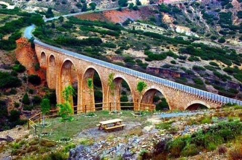 Viaducto de piedra de varios arcos por el que discurre la Vía Verde sobre un barranco de tierra roja