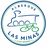 Albergue Las Minas Ojos Negros: emblema circular con una locomotora de vapor en azul y una bicicleta en verde